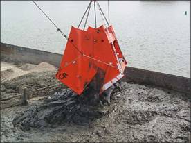large crane operated bucket dropping dirt onto barge